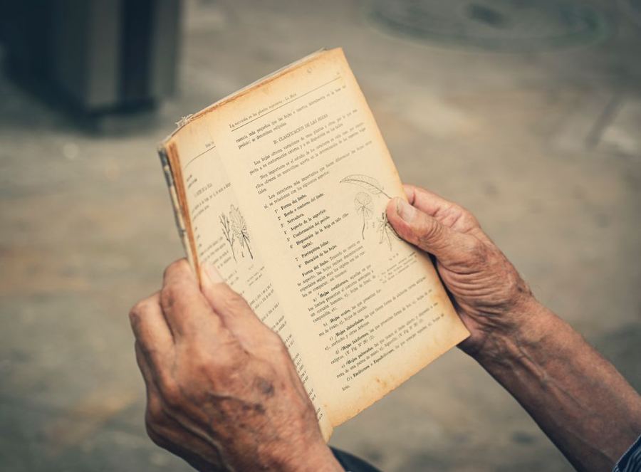 An older person’s hands resting on a book