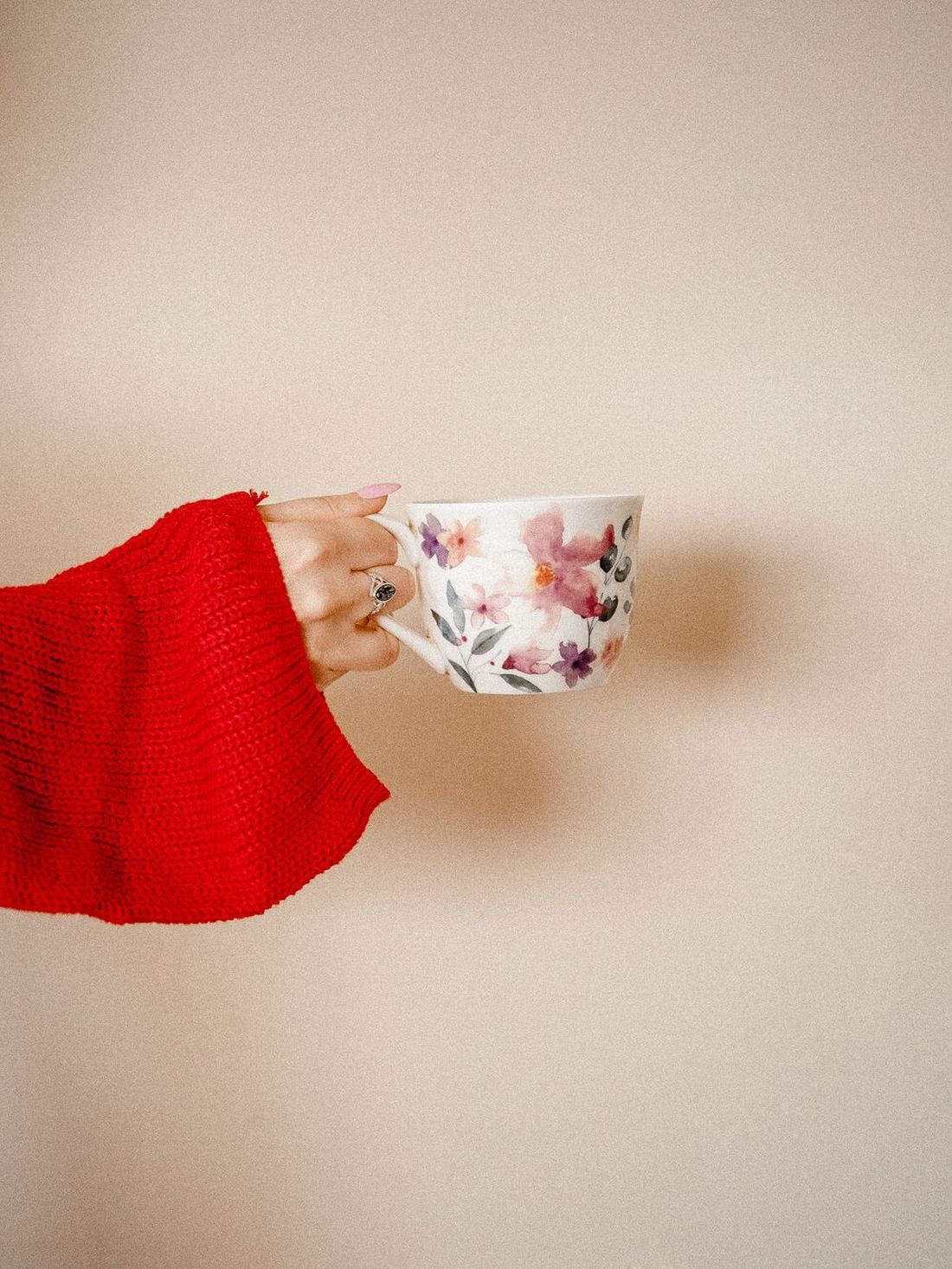 A pair of hands holding a floral china teacup
